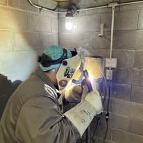 Plumber welding a gas line connection during a water heater installation in Boynton Beach
