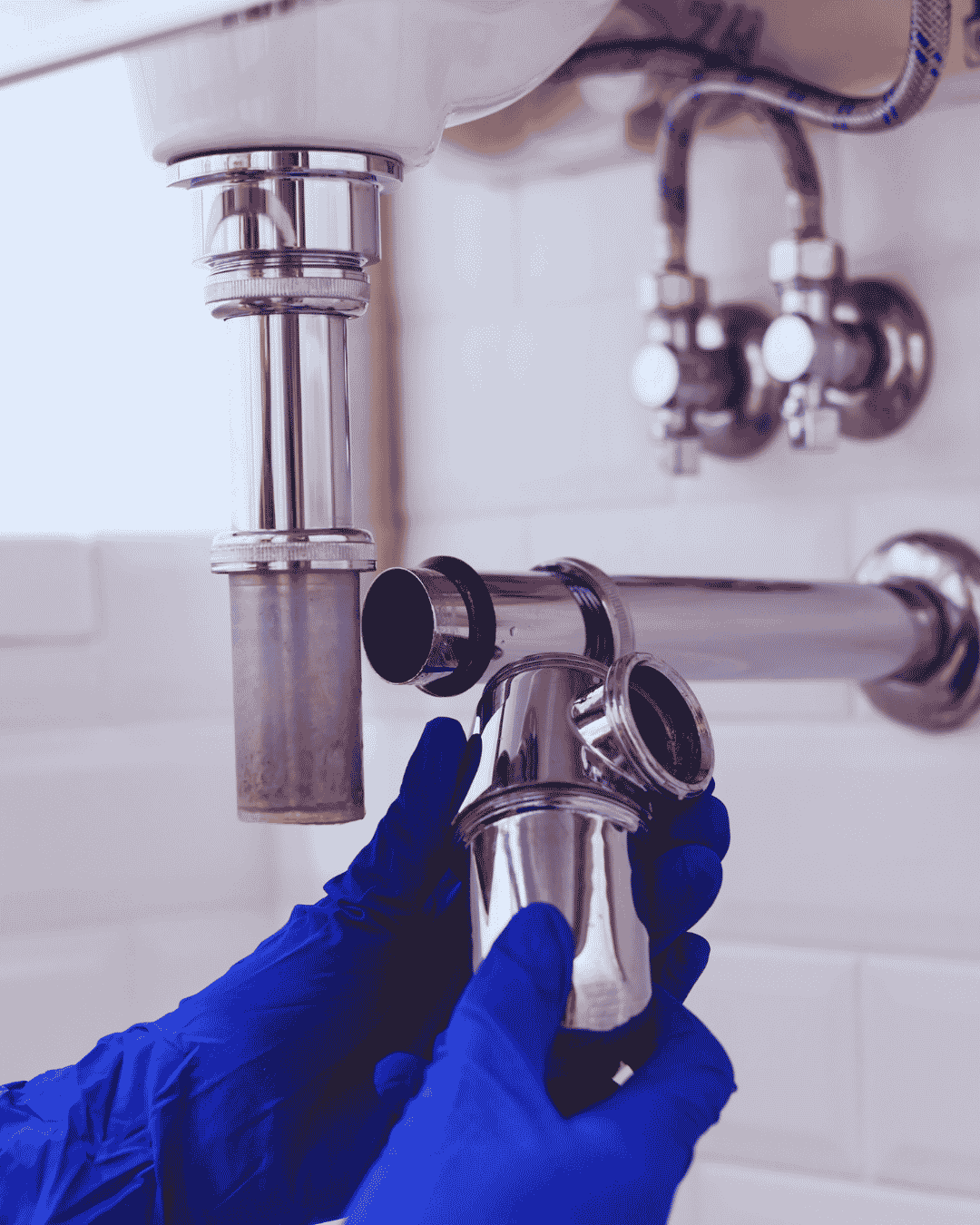 Licensed Boynton Beach plumber repairing a kitchen sink drain line under the cabinet